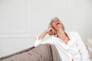 Best-Ager Frau lachend auf Sofa